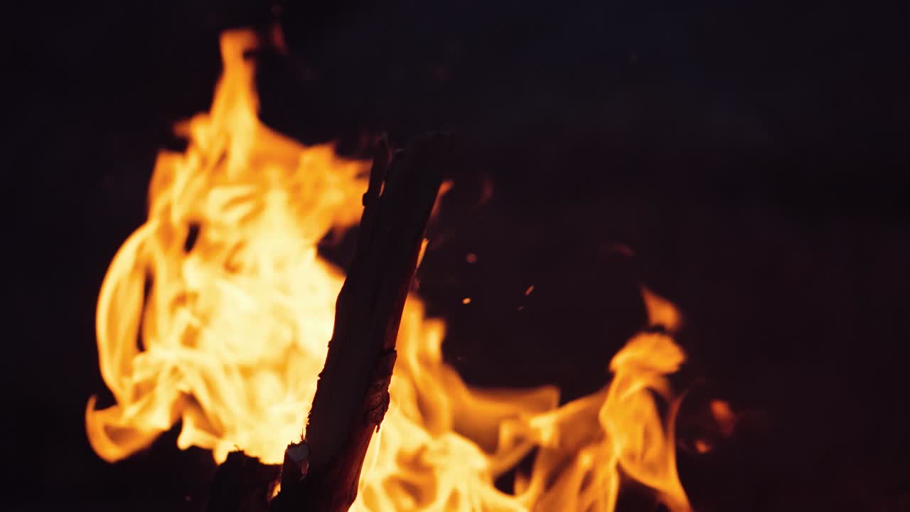 A closeup of a campfire. Beautiful fire burns brightly. Embers of the fire climb up. Slow motion