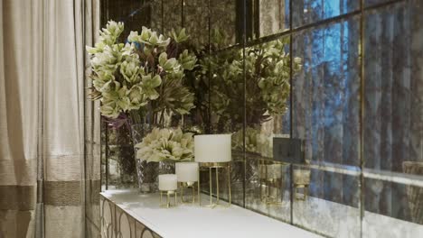 indoor plants and nordic decorations on console table against mirrored wall tiles