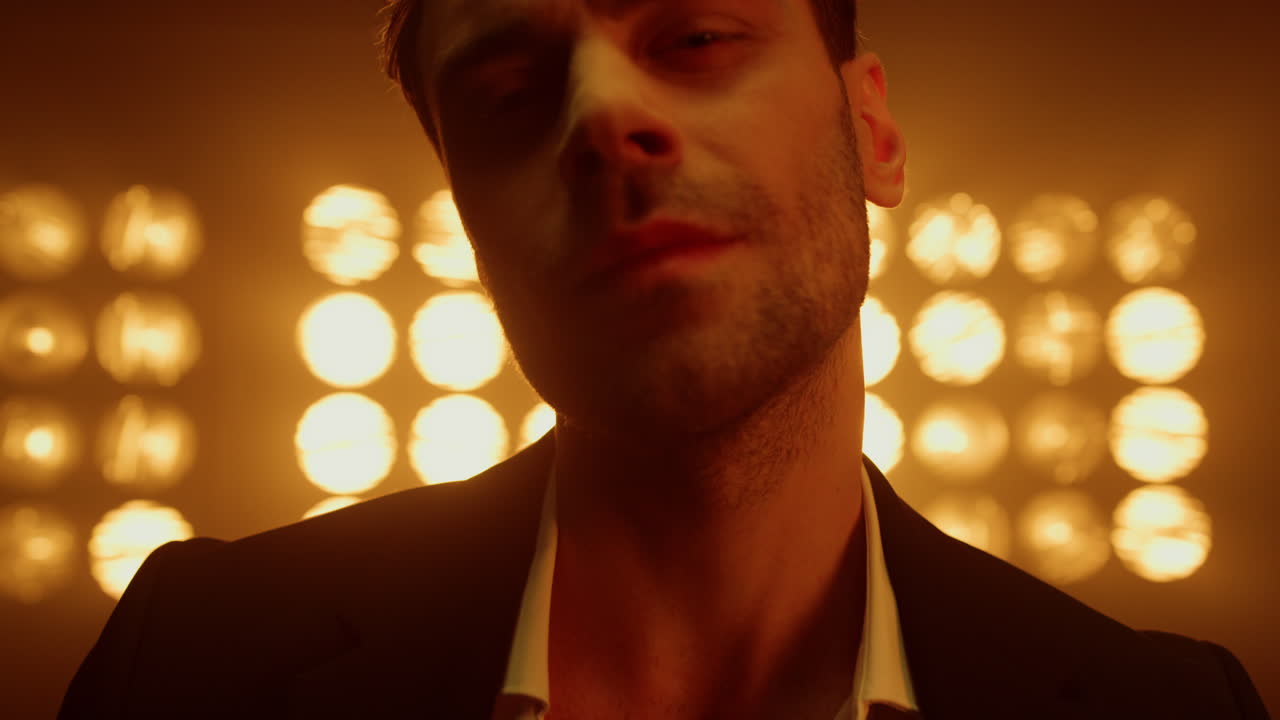hombre mirando cámara seductora en luces de club de primer plano. retrato de modelo masculino