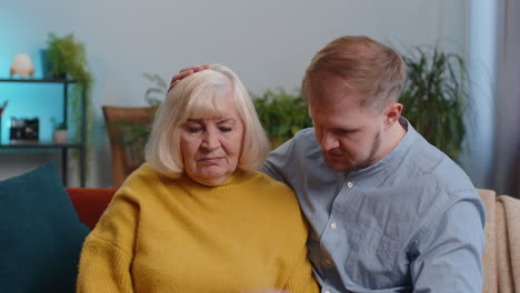 grown up son adult man supporting, giving psychological help to ill sick senior mother, compassion