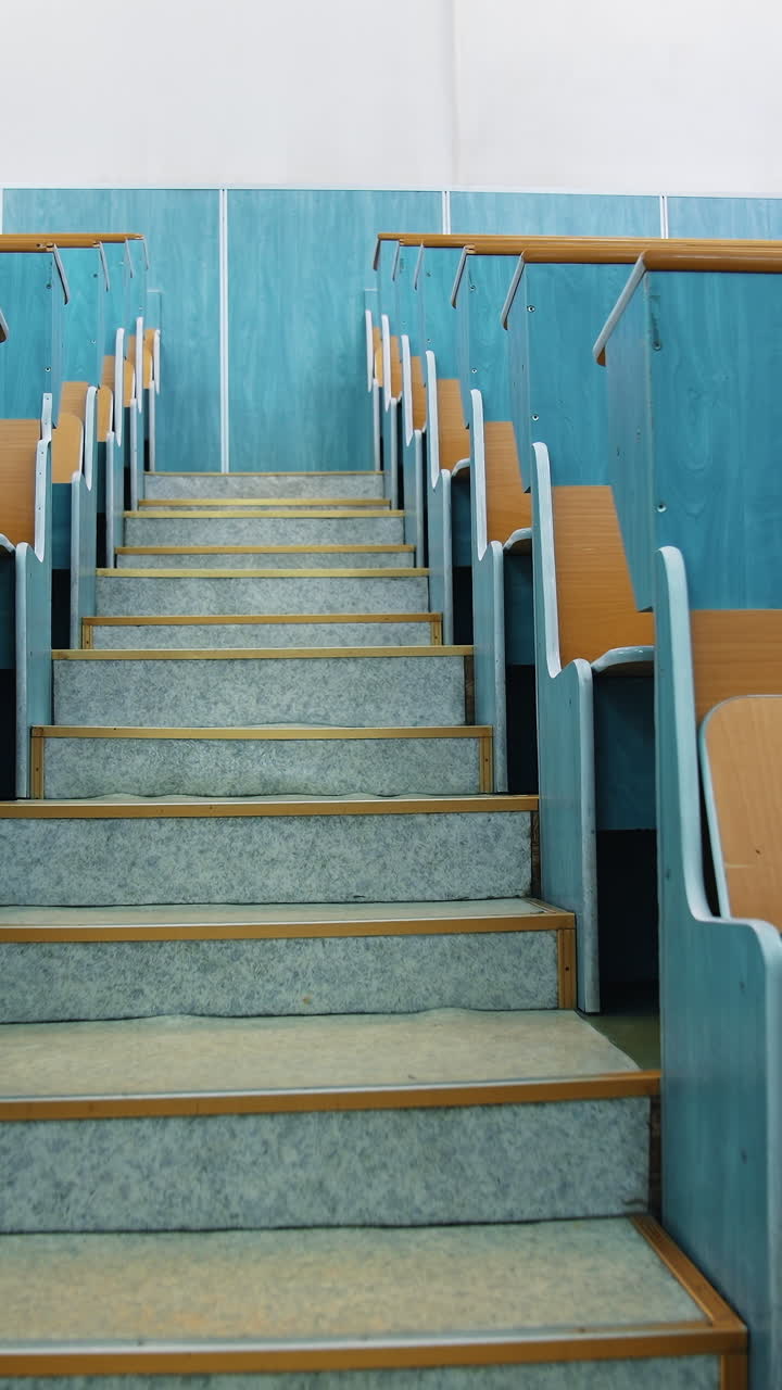 Empty auditorium. Stairs between two rows of desks in conference hall. Beautiful class for studying without students. Classroom in the university with wooden desks. Vertical video