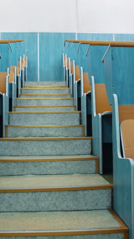 empty auditorium. stairs between two rows of desks in conference hall. beautiful class for studying without students. classroom in the university with wooden desks. vertical video