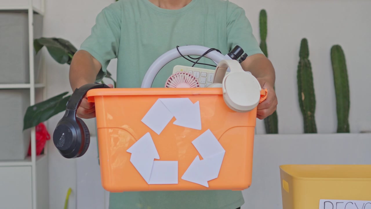 Close up of person presenting bin full of old electronics and tech devices for recycling