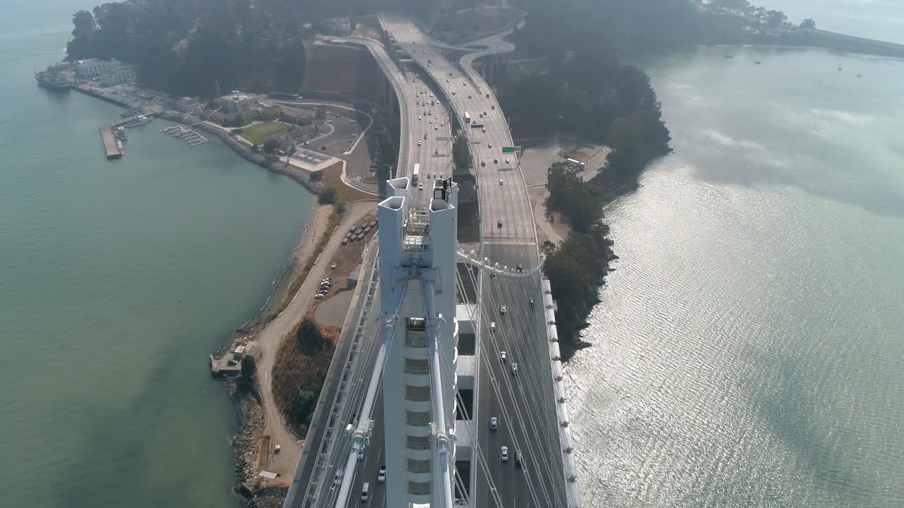 toma aérea de vehículos moviéndose en el puente de la bahía de san francisco–oakland con la ciudad al fondo