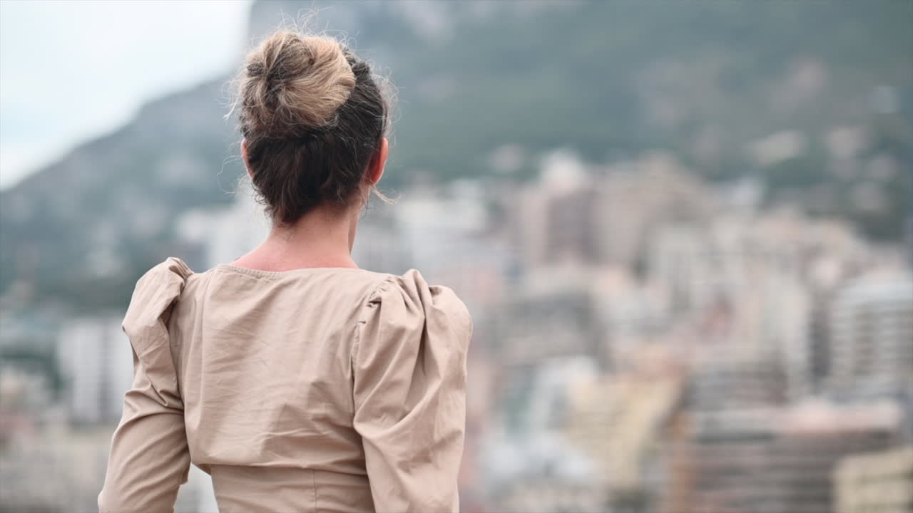 Woman in brown dress posing in Monte Carlo district, Monaco cityscape