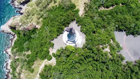 a birds eye view of the popular tourism landmark cristo rei statue and surrounding greenery and rugged shoreline in capital dili, timor leste