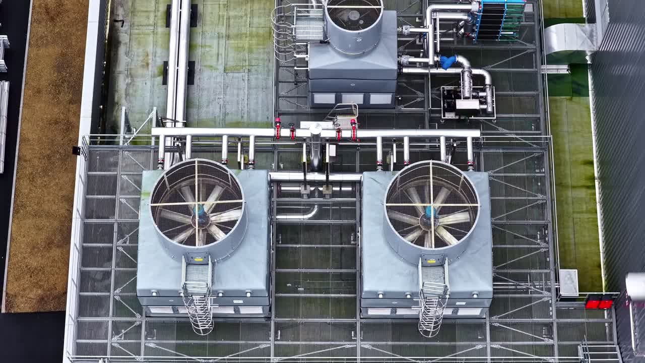 Two large cooling units and intricate pipe systems on an industrial rooftop. Useful for engineering or industrial infrastructure content