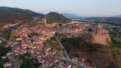 drone panning from the right to the left showing showing some houses and buildings by the hillside of a village in valderama, spain.