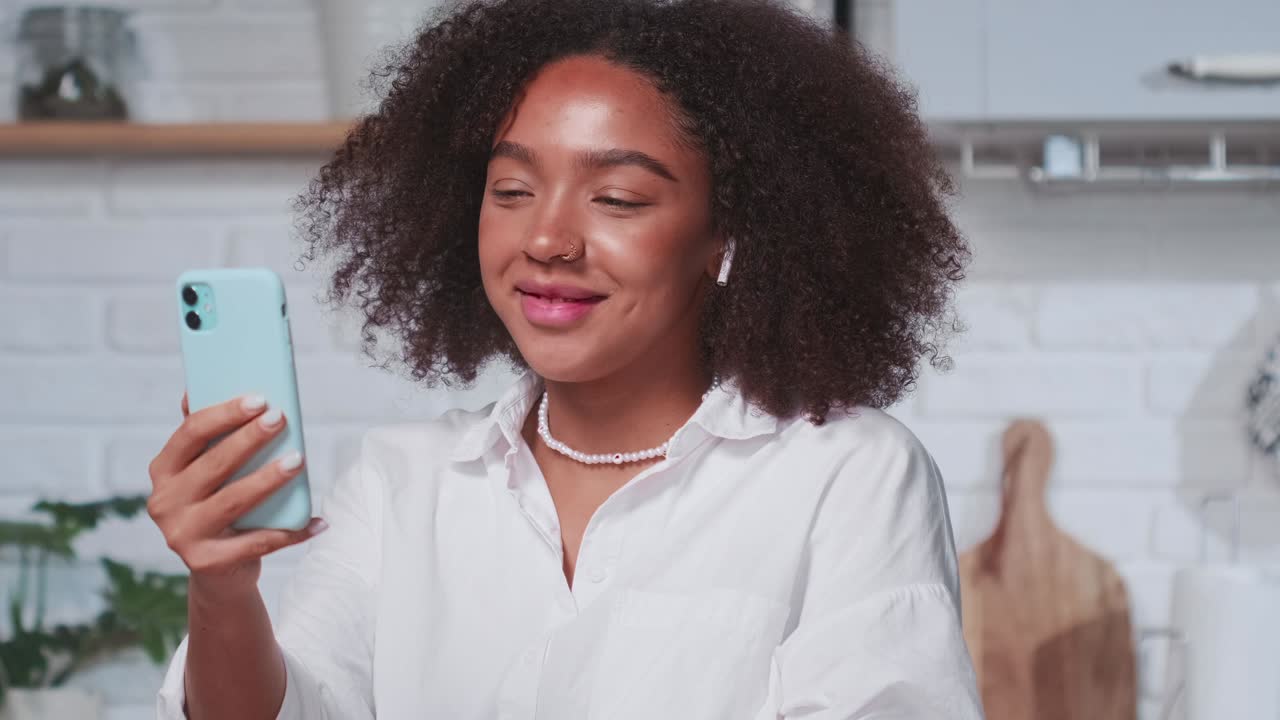Cheerful young african american woman waves and smiles during video call