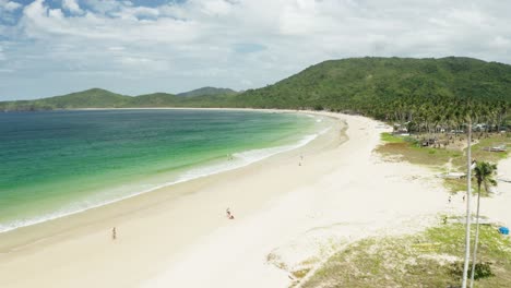 drone shot through palm trees of nacpan beach, el nido, palawan, philippines