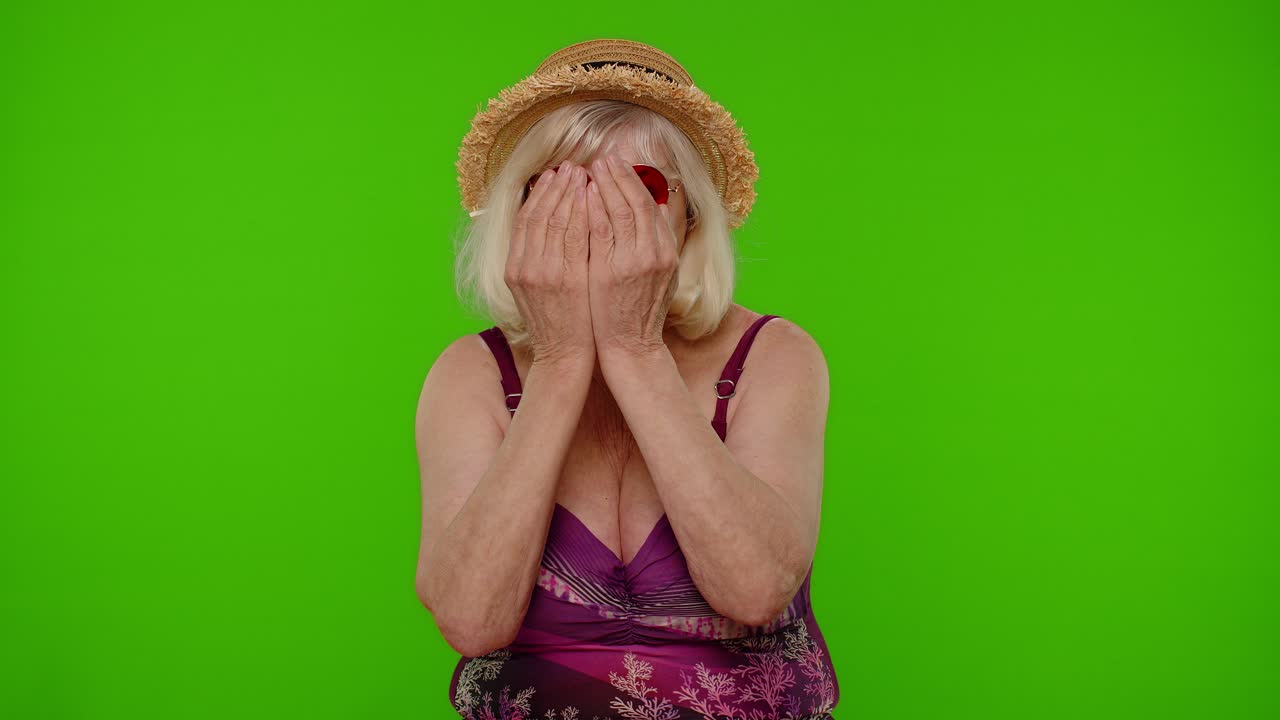 Anziana donna turista divertente e sciocca in costume da bagno, che scherza facendo un'espressione stupida e insensata.