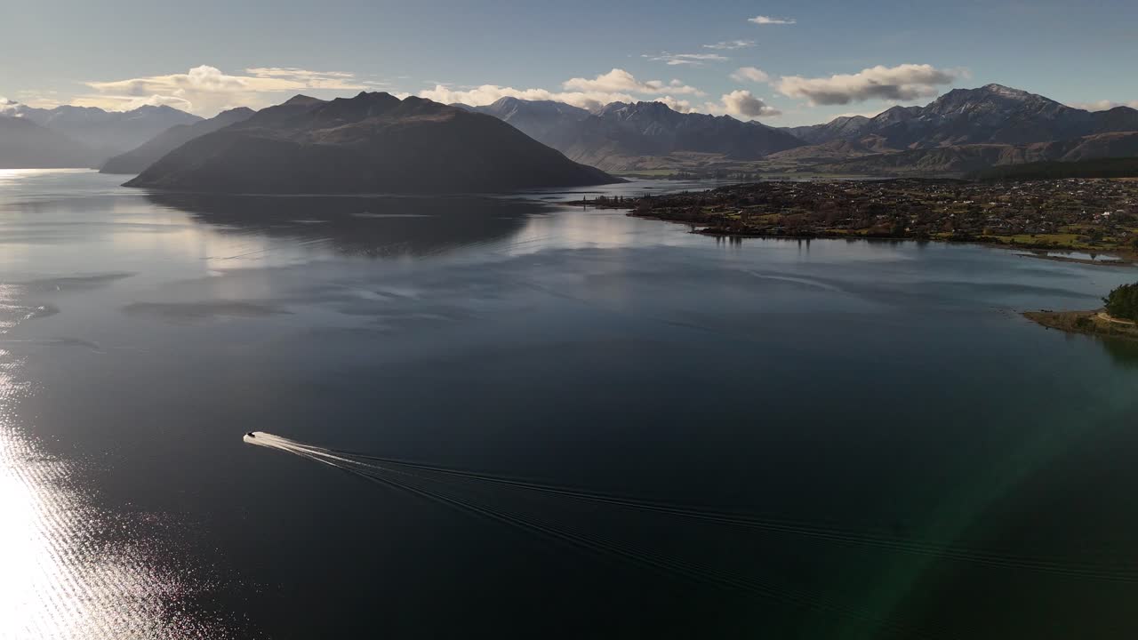 Beautiful view of Lake Wanaka with a boat sailing across it. The mountains in the background