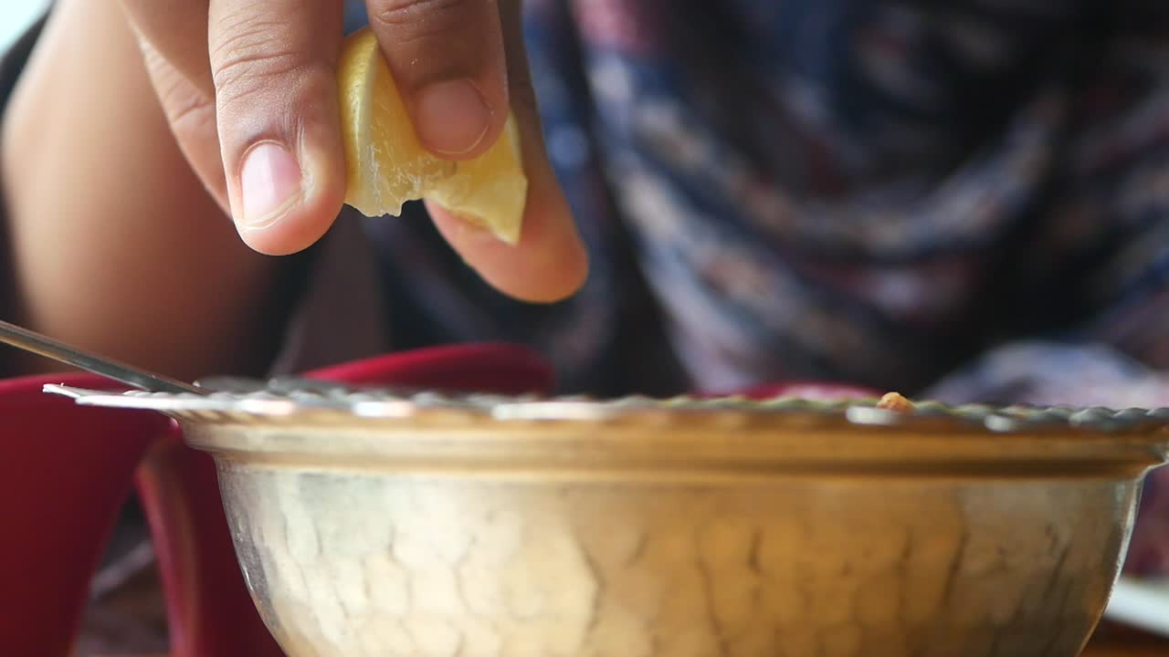 Person Squeezing Lemon Juice Over Bowl