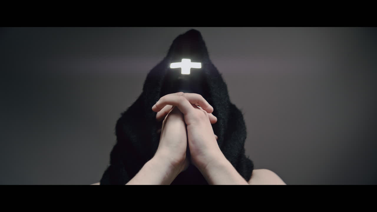 Masked man with cross of light glowing on his face moves his head up