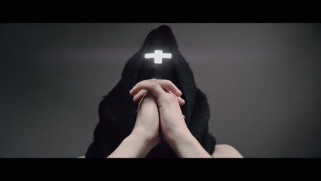 masked man with cross of light glowing on his face moves his head up