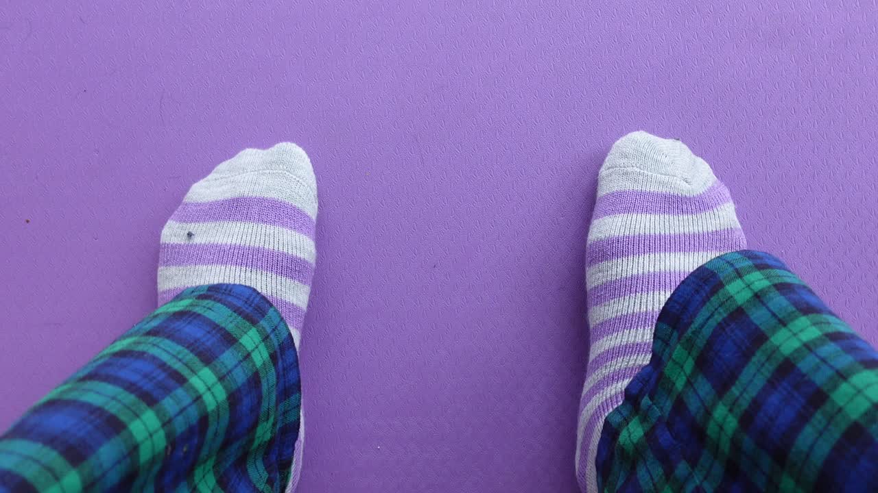 Person Wearing Pajamas and Striped Socks on a Purple Mat