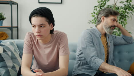 teenager and father arguing on couch