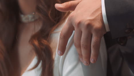 newlywed man in tuxedo strokes arm of bride at wedding