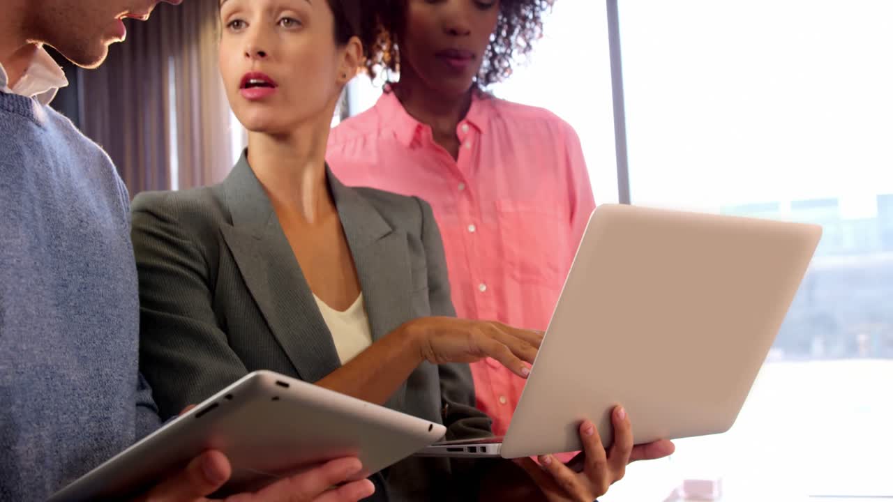 Colegas discutindo sobre um laptop e um tablet digital