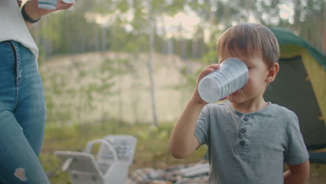 Kleiner-Junge-Trinkt-Wasser-Aus-Glas-Im-Zeltlager-Im-Wald-Im-Sommer.-Familie-Ruht-Sich-In-Der-Natur-Aus