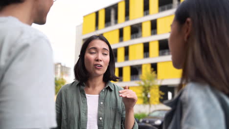 una mujer japonesa bastante joven hablando con sus dos amigos mientras están juntos al aire libre en la calle