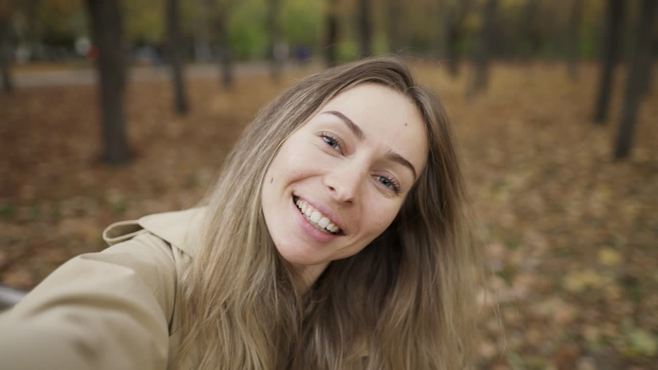 mujer caucásica tomando una foto selfie en un teléfono inteligente al aire libre en el parque mientras camina