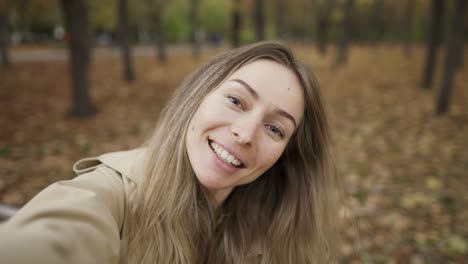 Mujer-Caucásica-Tomando-Una-Foto-Selfie-En-Un-Teléfono-Inteligente-Al-Aire-Libre-En-El-Parque-Mientras-Camina