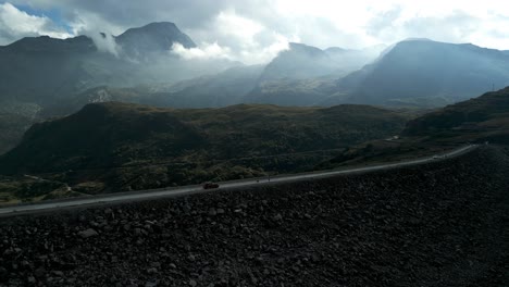 aerial view of car driving along mont cenis dam with dramatic mountain landscape in background