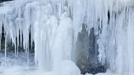 slow motion shot of water pouring down a frozen waterwall