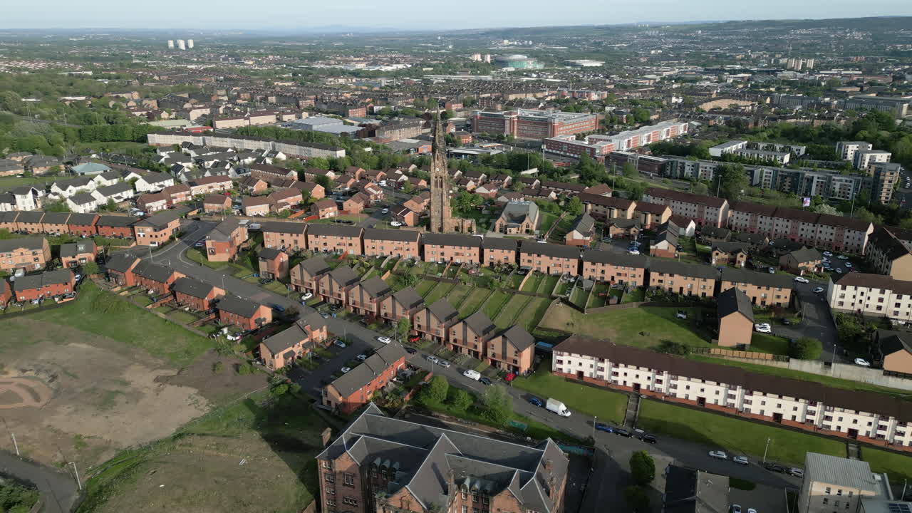 Un'orbita aerea cinematografica intorno alla storica chiesa parrocchiale di Royston TownheadBlochairn con lo stadio di calcio Celtic visibile sullo sfondo del panorama urbano di Glasgow