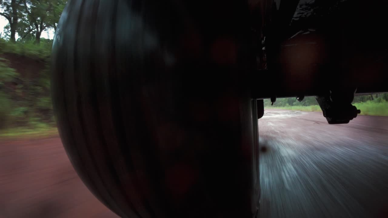 Clip video POV (point of view) con ripresa posteriore di un pneumatico 4x4 fuoristrada che si muove velocemente su una strada sterrata e fangosa a Cape York, in una remota zona dell'Australia