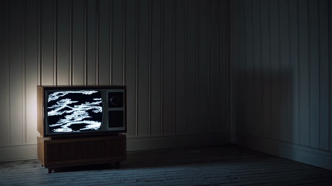 A vintage TV displaying static in a dimly lit room, captured from a low angle