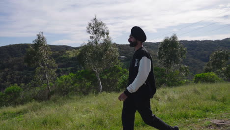 Hombre-Sikhi-Con-Barba-Tupida-Caminando-Por-Las-Verdes-Colinas-Con-Paisajes-Naturales