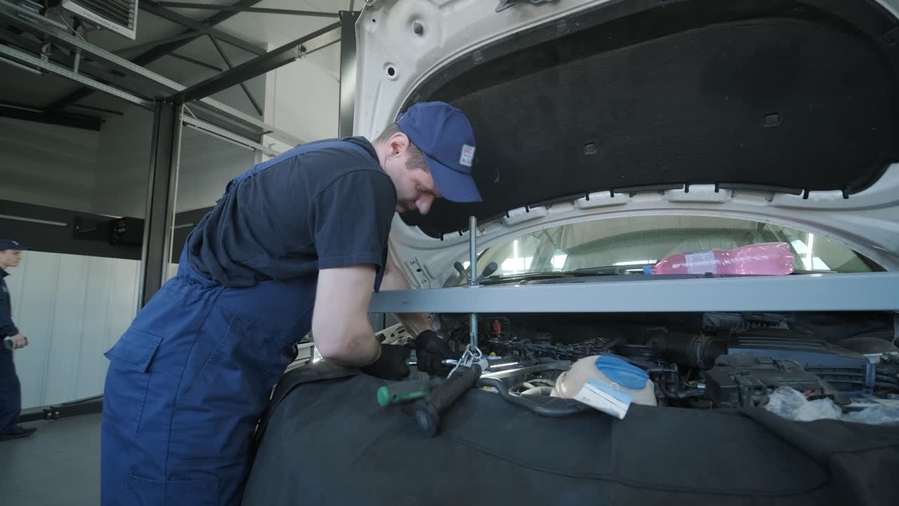 mecánico de automóviles inspeccionando el motor del automóvil en el taller