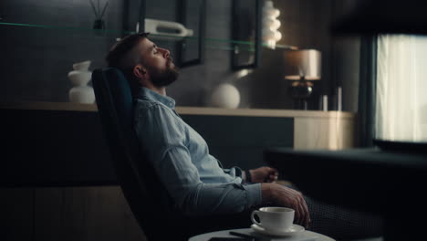 professional financial analyst sitting in chair with closed eyes, resting after work and hard trading day. successful businessman in comfortable home office or investment bank office. dolly shot.
