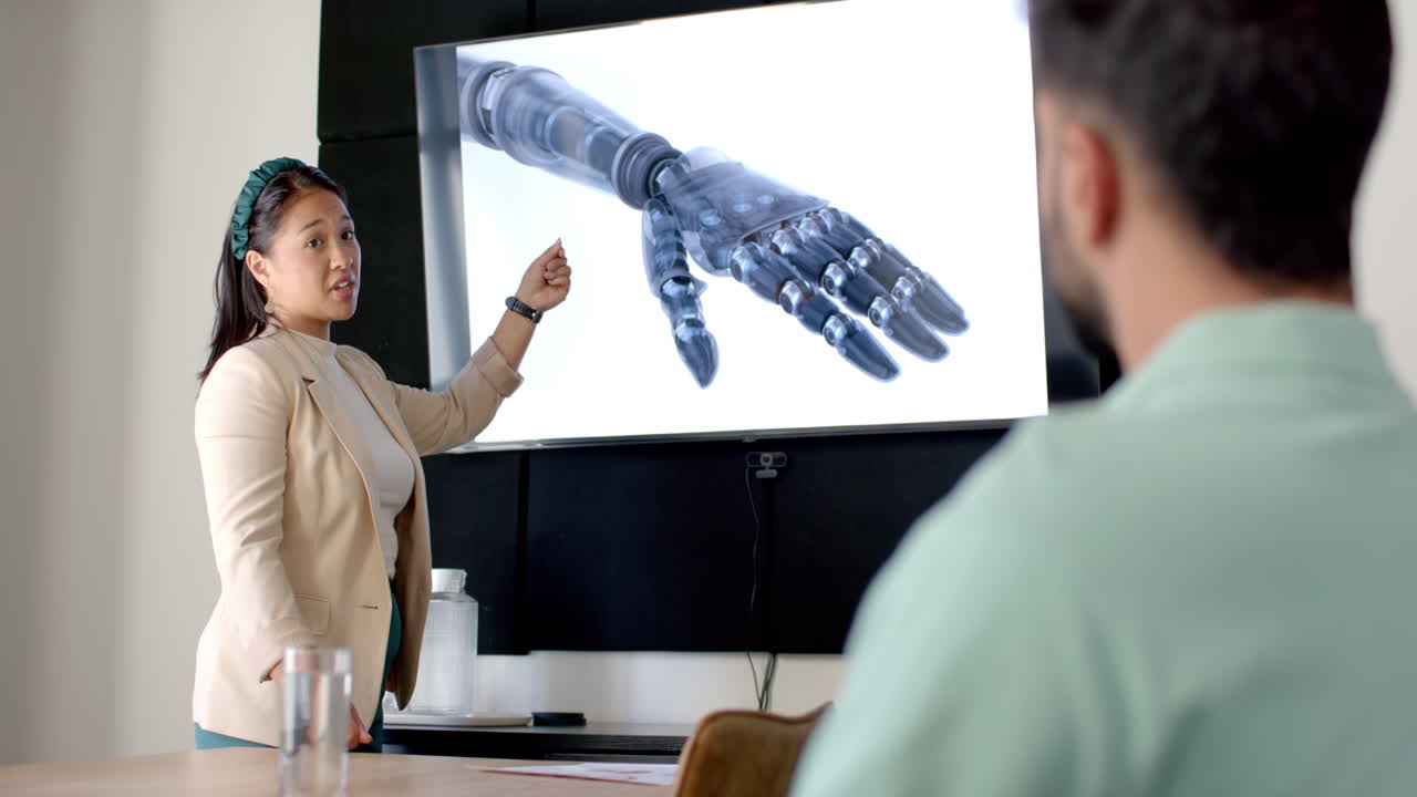 Presenting robotic arm, woman pointing at screen in office meeting