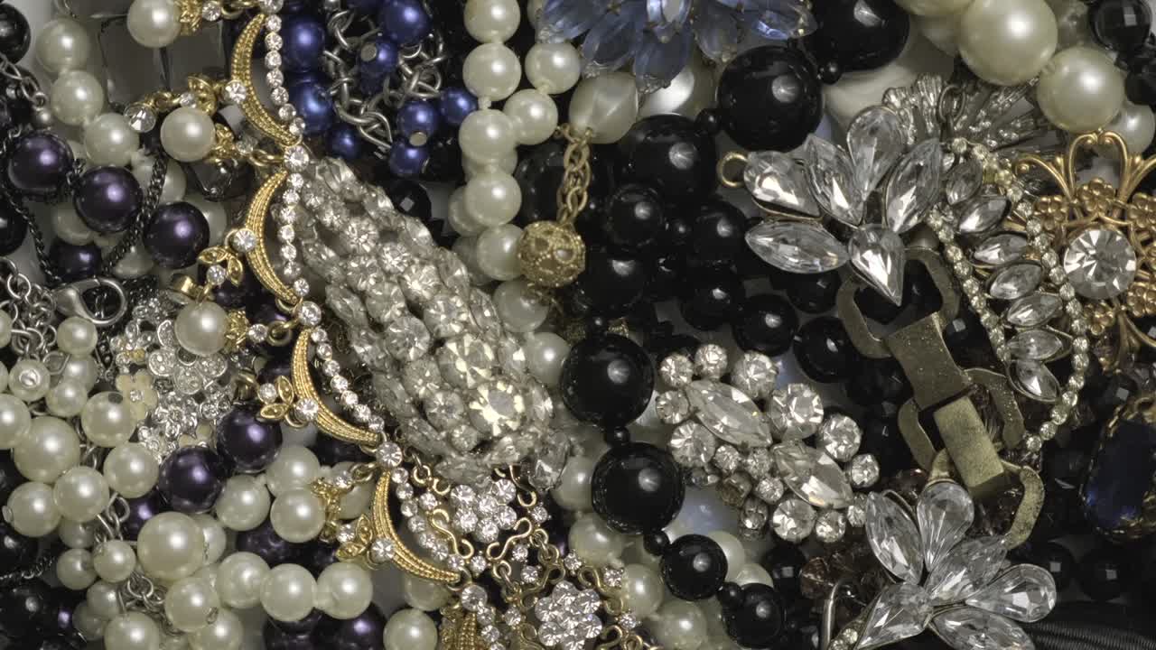 conjunto de joyas, fondo de rotación de oro amarillo y blanco. muchas hermosas joyas de moda femeninas con piedras preciosas brillantes, perlas y diamantes para mujeres. riqueza y concepto de lujo, primer plano, macro