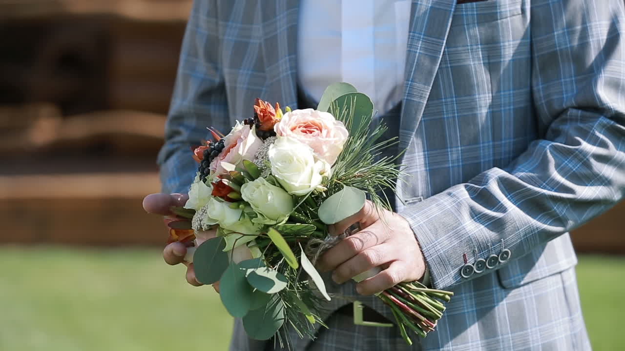 Wedding bouquet with beautiful flowers in the hands of the groom