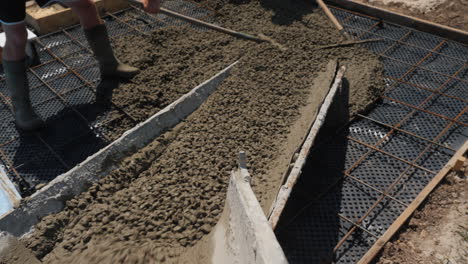 concrete flows down the gutters where workers make paving 5