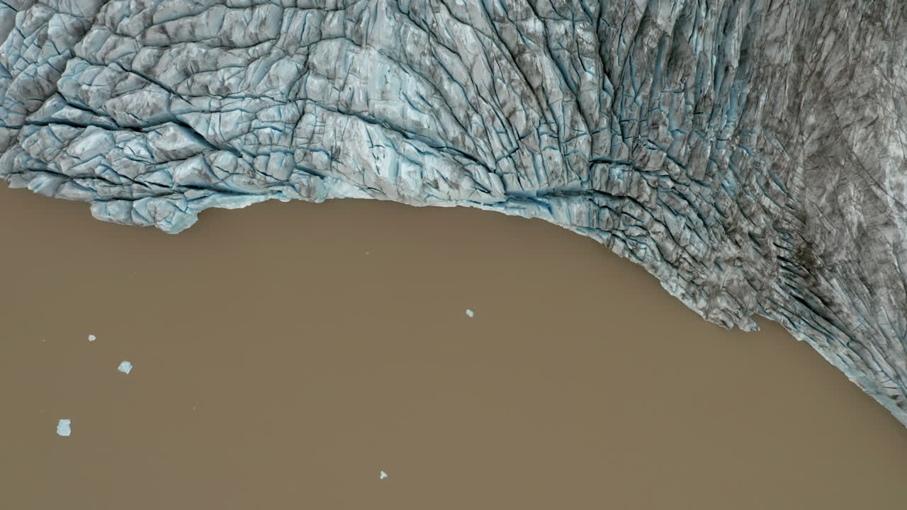antena: vista de arriba hacia abajo del borde del glaciar en el agua de la laguna marrón