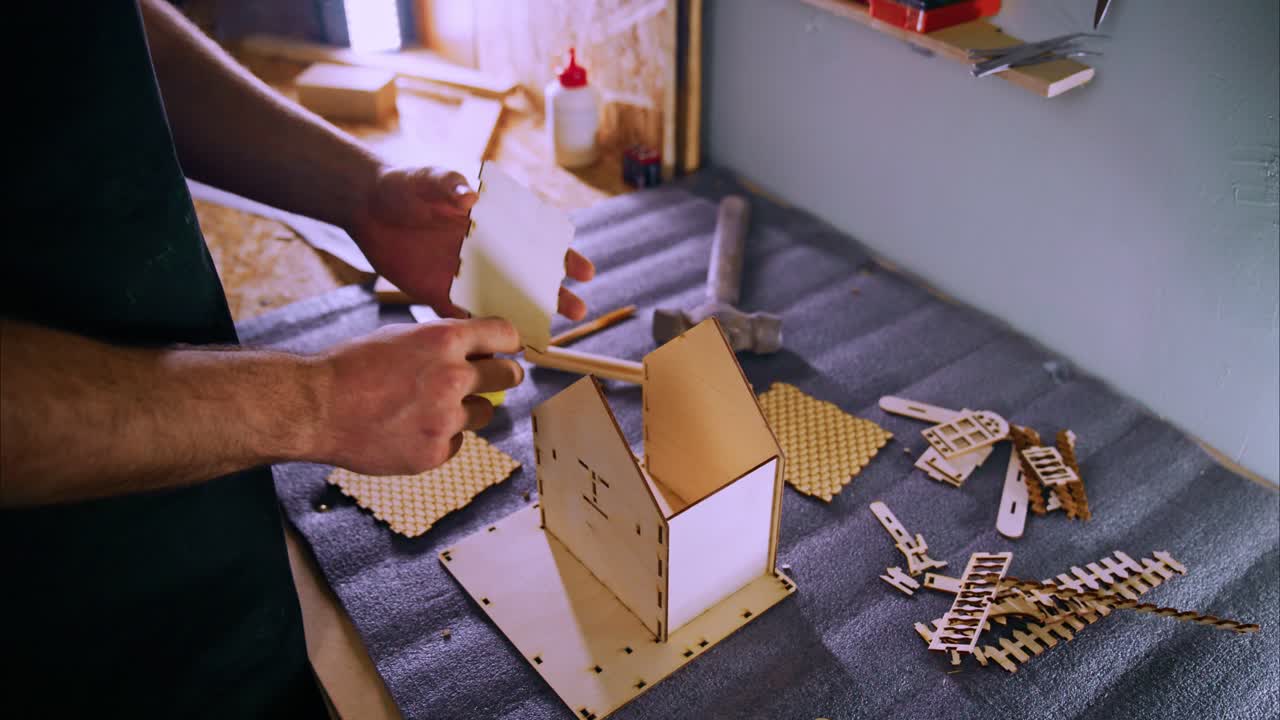 Primo piano di mani che creano una casetta in miniatura di legno