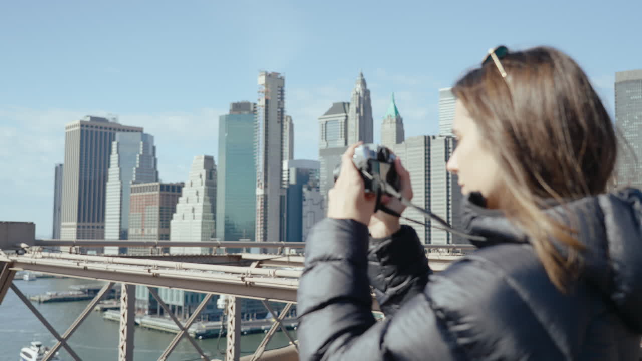 Woman taking a photo of NYC skyline from Brooklyn Bridge