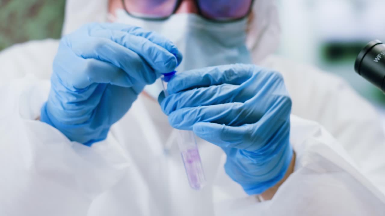 Scientist in Protective Gear Pipetting Liquid into Test Tube