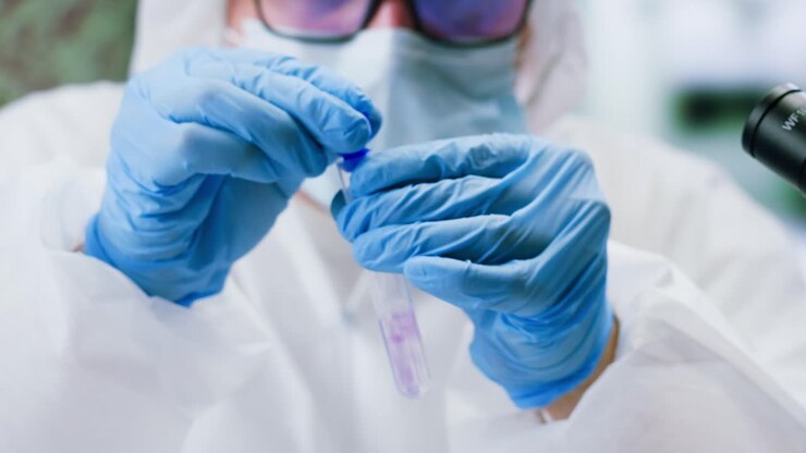 Scientist in Protective Gear Pipetting Liquid into Test Tube