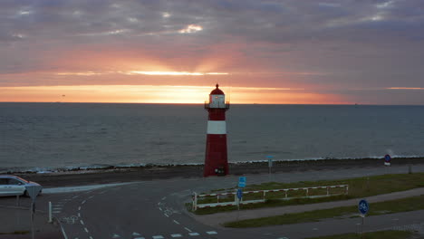 the lighthouse of westkapelle during a bright orange sunset, with a lot of wind