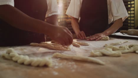 Animation-of-hands-of-diverse-female-and-male-bakers-preparing-rolls-at-bakery