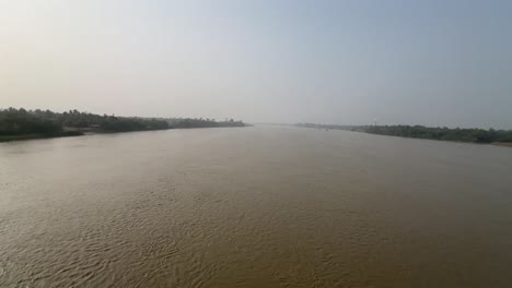 wide angle shot of a muddy river hoogly flowing during sunset in bengal, india