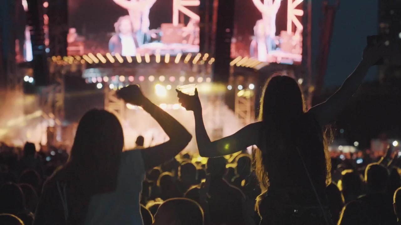 Ung kvinde båret på skuldre i en jublende folkemængde til en musikfestival