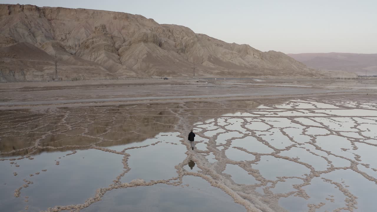 Person Walking Through Salt Flats in Desert Landscape
