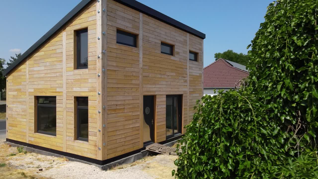 Modern prefabricated wooden house with angled roof and natural facade